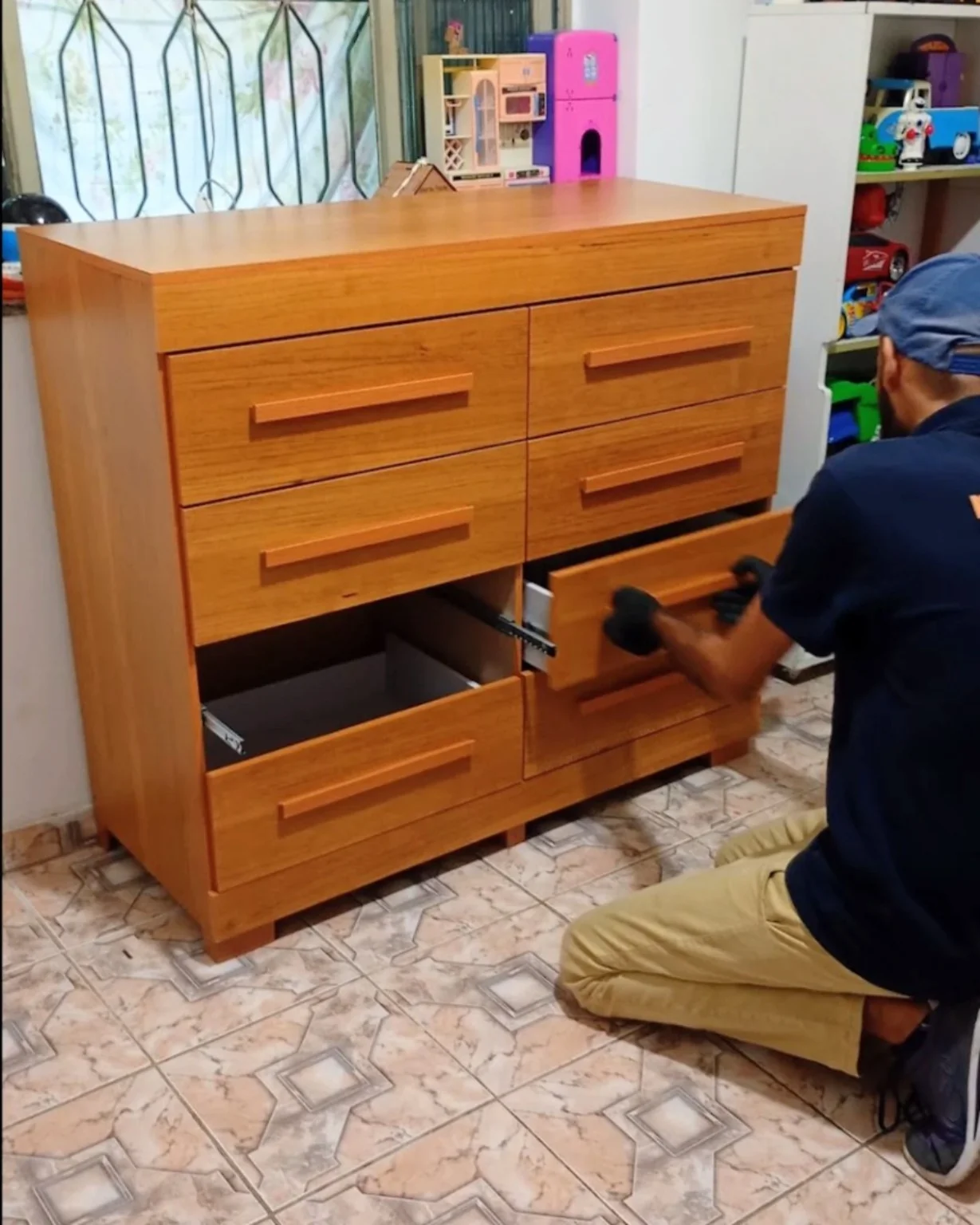 Montador uniformizado ajustando as gavetas de uma cômoda